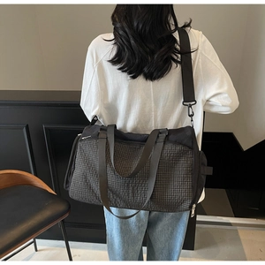 Detailansicht einer Reisetasche mit Karomuster, robusten Gurten und Seitenfächern