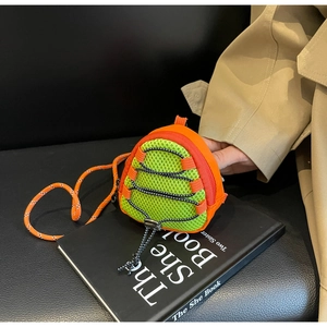 Close-up of orange and green mesh mini crossbody bag on book with woven strap detail
