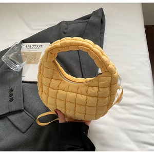 Détail du sac matelassé jaune avec surpiqûres carrées sur fond de blazer gris élégant
