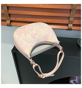 Detail view of pink floral half-moon bag with golden zipper and textured finish