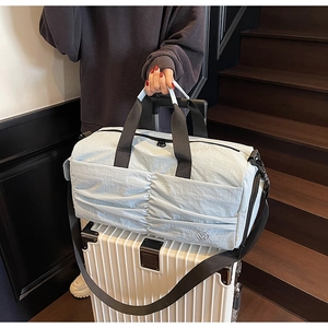 Close-up of light blue travel duffel bag on a white suitcase with adjustable shoulder strap