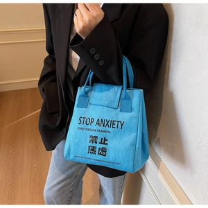 Detail of blue waterproof Tyvek tote bag featuring Stop Anxiety text and webbing handle