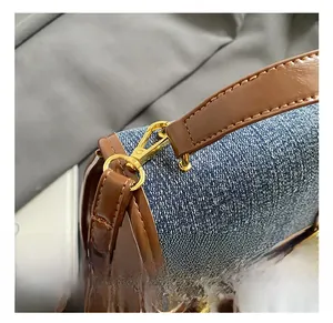 Detail shot of the blue denim backpack featuring a premium gold metal hook and leather strap