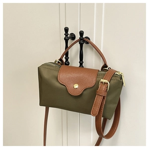 Detail of olive green nylon bag with brown leather strap and gold snap closure