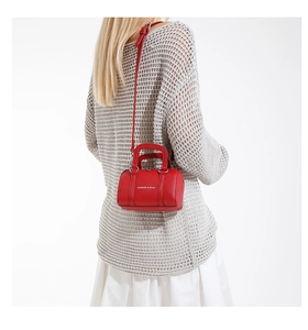 Mini sac Boston rouge en cuir grainé porté par un mannequin avec inscription blanche