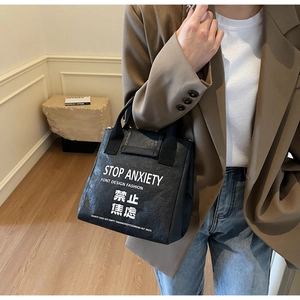 Detail of Tyvek waterproof tote with Stop Anxiety slogan in a stylish street style setting