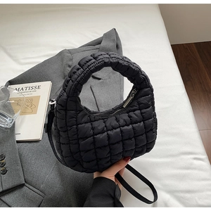 Gros plan d'un sac nuage matelassé noir avec poignée ronde sur fond blanc épuré