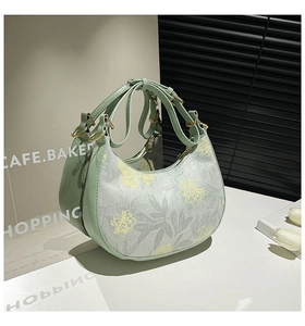 Detail of light green crescent bag with floral print and adjustable shoulder strap