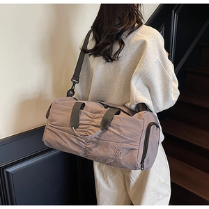 Detail view of mauve travel bag showing wrinkled nylon texture and brand embroidery