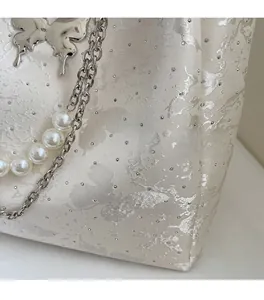 Gros plan d'un sac cabas en jacquard avec breloque papillon argentée et chaîne de perles