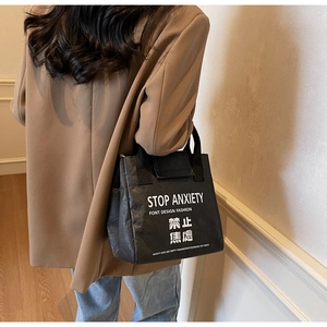 Detail of waterproof black Dupont paper tote bag featuring the Stop Anxiety white slogan