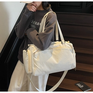 Detail der weißen Reisetasche mit Waffelstruktur, Doppelgriffen und abnehmbarem Schultergurt