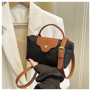 Detail showing the brown leather flap and golden snap button of the nylon handbag