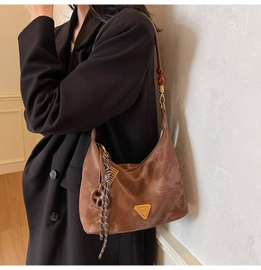 Brown half-moon shoulder bag with amber bead strap and gold triangle logo pendant