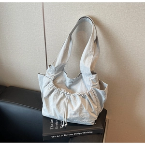 Close-up of light grey pleated tote bag with drawstring detail and magnetic closure