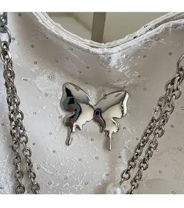 Gros plan d'un sac en satin blanc avec papillon argenté et détails en perles chic