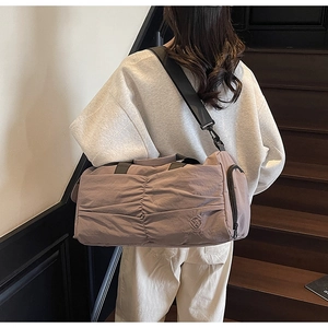 Detail of the pink travel bag with brand embroidery and adjustable shoulder straps