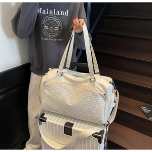Details der cremefarbenen Reisetasche mit gesteppter Tasche und Trolley-Halterung