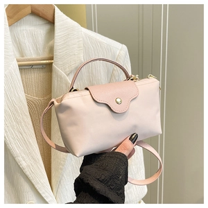 Detail of light pink nylon handbag with litchi grain leather flap and gold metal buckle