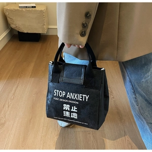 Detailed view of the black Tyvek tote bag featuring a white Stop Anxiety slogan print