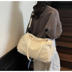 Rückansicht eines Modells mit beiger Reisetasche mit Steppmuster und breiten Trägern