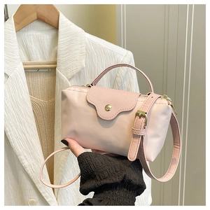 Detail of light pink nylon handbag featuring fine leather texture flap and golden button