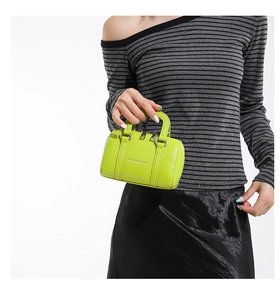 Gros plan d'un mini sac boston vert néon avec marquage argenté et texture cuir grainé