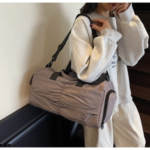 Detail of grey-purple duffel bag featuring stylish pleated fabric and brand embroidery