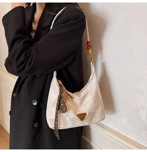 Detail of hobo shoulder bag with metal triangle logo and amber bead strap accents