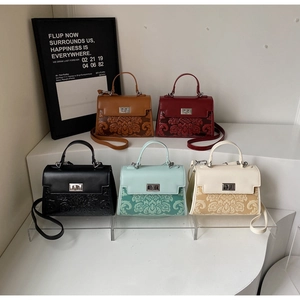 Detailed display of five small square handbags with embossed floral patterns and metal buckles