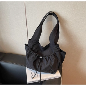 Close-up of black tote bag featuring a silver drawstring closure and side pockets