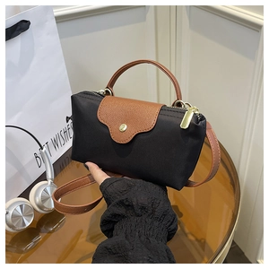 Detail of mini black nylon tote with brown leather flap and golden hardware accents