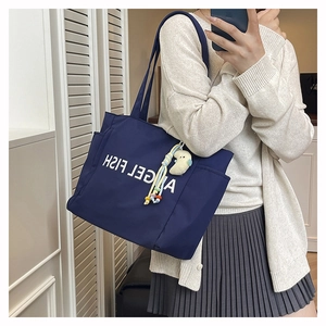 Détail du sac fourre-tout en nylon bleu foncé montrant le logo blanc et la poche latérale