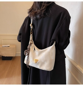 Detail of cream nylon hobo bag with gold triangle logo and brown woven knot charm