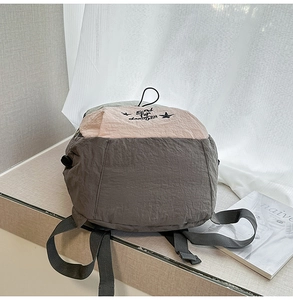 Detail of minimalist two-tone backpack with embroidery and crinkle texture fabric