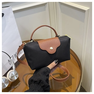 Detail of mini nylon handbag with brown leather flap and golden snap closure
