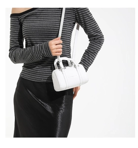 Macro shot of white mini barrel bag with lychee texture leather and silver hardware details