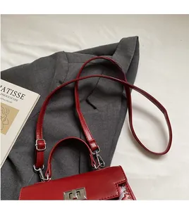 Detail of red glossy leather handbag featuring silver metal twist lock and adjustable strap