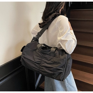 Detailed view of black travel bag showing pleated texture and adjustable shoulder strap