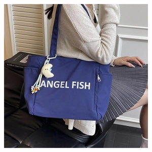Détail du sac cabas en nylon bleu marine avec inscription blanche et breloque jaune
