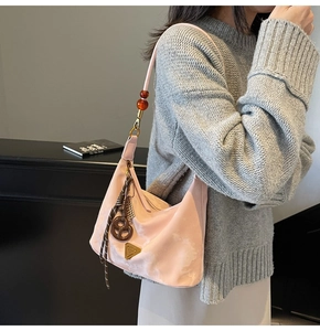 Dettaglio della borsa sottobraccio rosa con placca a triangolo e tracolla con perline