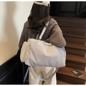 Details der hellgrauen Reisetasche mit Wellenstruktur, verstellbarem Gurt und großem Volumen