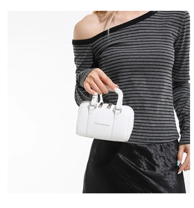 Close-up of a white mini Boston bag with lychee texture held by a model in a casual outfit