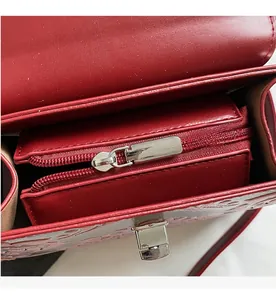 Macro view of red leather crossbody bag showing smooth zipper and metal twist lock