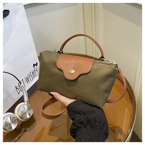 Detail of army green nylon mini bag with brown leather handles and shoulder strap