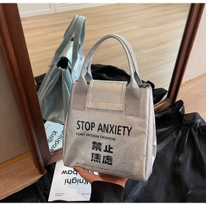 Detail of silver Dupont paper tote with Stop Anxiety print and reflective texture