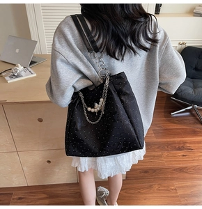 Détail du sac cabas noir à motifs étoilés, chaîne argentée et breloques en perles sur la sangle