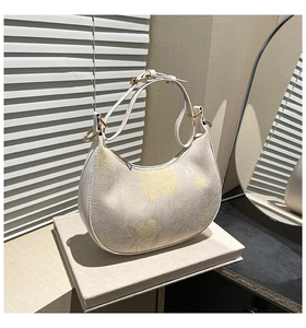 Detail of white jacquard hobo bag featuring floral patterns and gold metal hardware