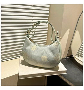 Detail of light green suede hobo bag with yellow floral print and gold hardware