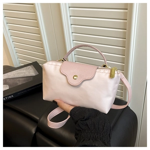 Detail of pink nylon mini dumpling bag showing leather flap and golden button hardware
